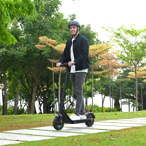 Homme casqué roulant sur l'Inmotion Air sur un chemin dans un parc