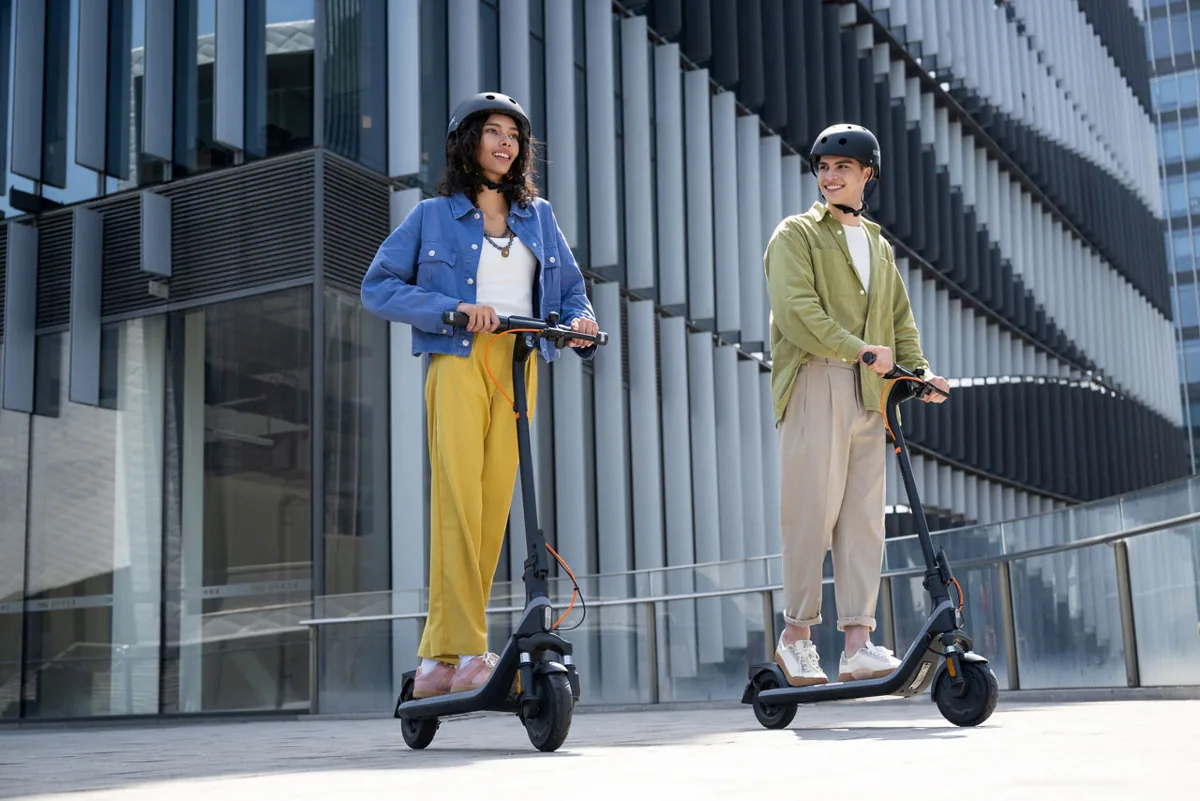 Deux personnes debout sur des Segway-Ninebot E2 Plus E II devant un immeuble vitré