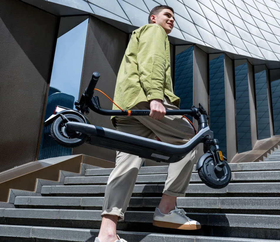 Homme portant une Segway-Ninebot E2 Plus E II pliée en descendant un escalier en ville