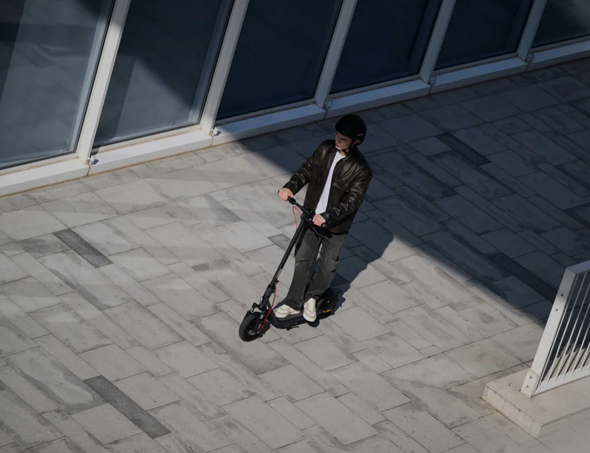 Homme roulant en Segway-Ninebot F2 Pro E II sur un pavé ensoleillé, vu d'en haut