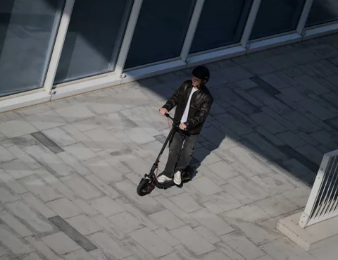Homme roulant en Segway-Ninebot F2 Pro E II sur un pavé ensoleillé, vu d'en haut