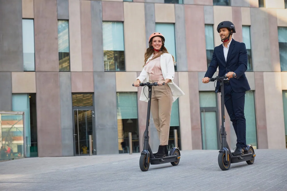 Homme et femme roulant en Segway-Ninebot MAX G30E II devant un immeuble