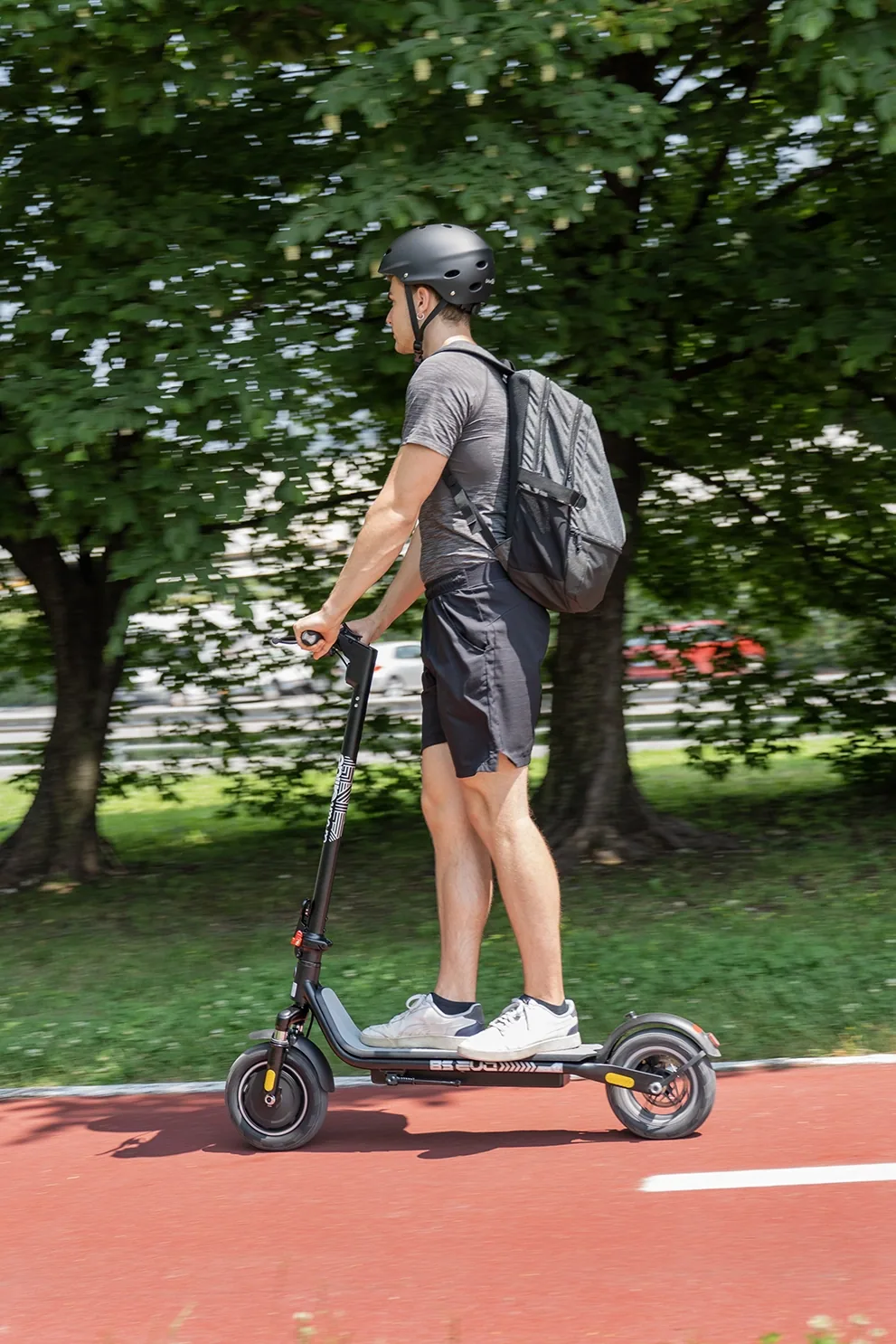 Un homme casqué roule sur une piste cyclable rouge avec l'Urbanglide Ride 85 Evo