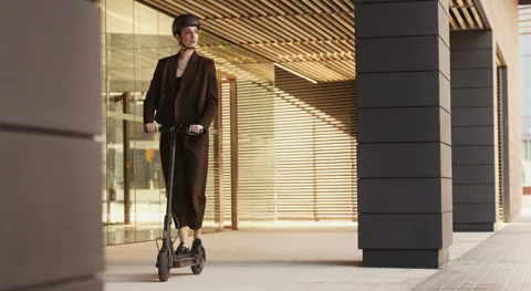 Femme casquée roulant sur la Mi Electric Scooter 1S sous des arcades