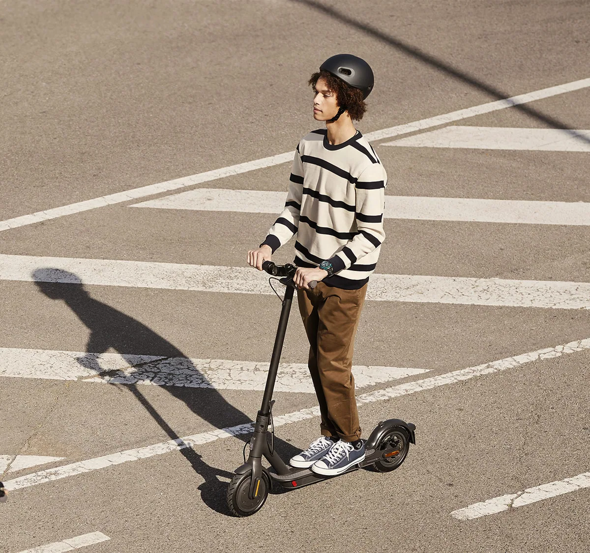 Homme roulant sur un passage piéton avec la Mi Electric Scooter Essential noire