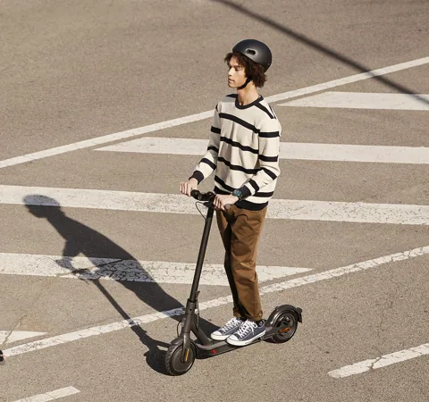 Homme roulant sur un passage piéton avec la Mi Electric Scooter Essential noire