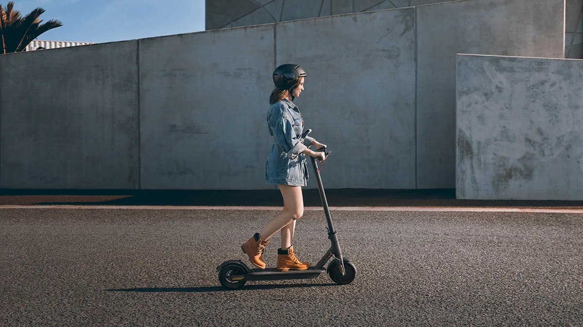 Femme casquée roulant sur la Mi Electric Scooter Pro