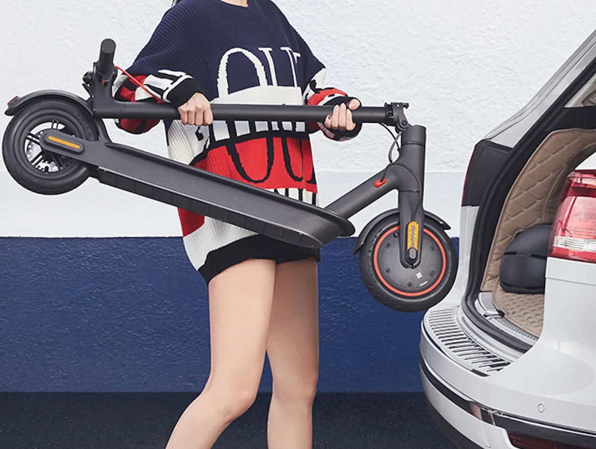Femme sortant une Mi Electric Scooter Pro pliée du coffre d'une voiture