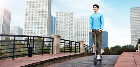 Homme roulant sur une passerelle en ville avec la Mi Electric Scooter (M365)