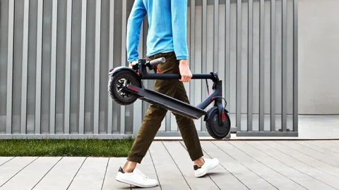 Homme portant à la main sa Mi Electric Scooter (M365) pliée