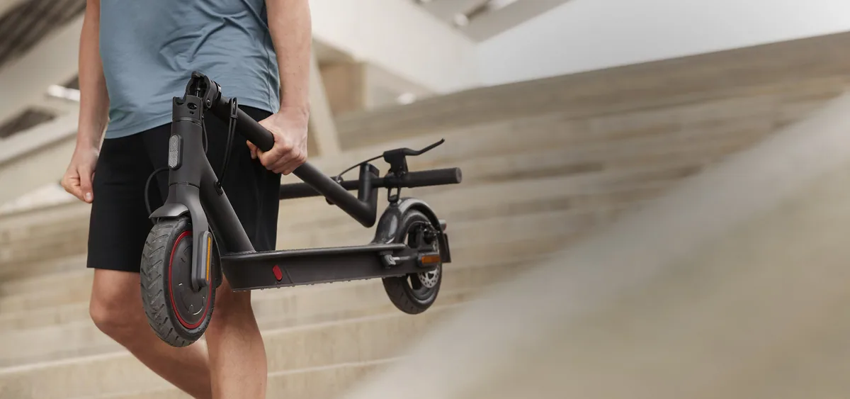 Homme portant sa Mi Electric Scooter Pro 2 pliée