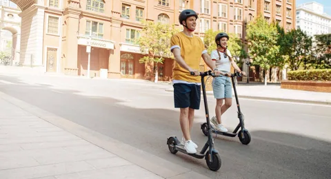 Deux personnes casquées roulant sur des Mi Electric Scooter 3 dans une rue