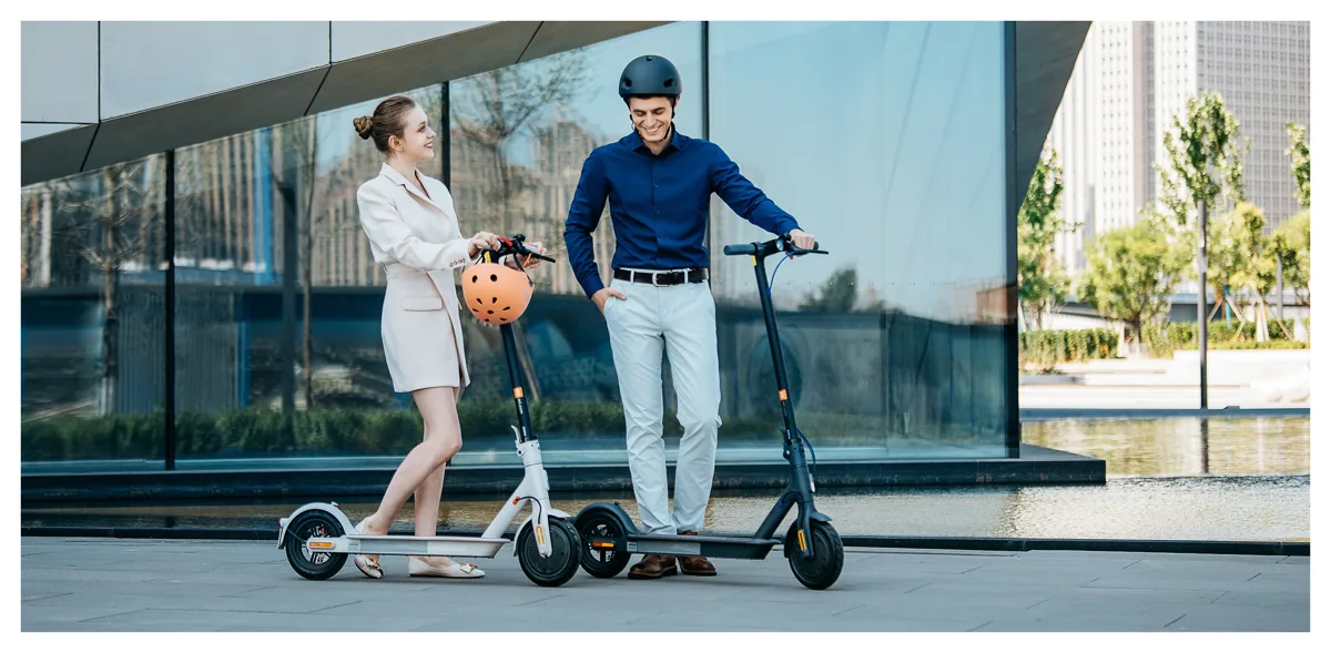 Deux personnes avec leurs Mi Electric Scooter 3 devant un immeuble vitré