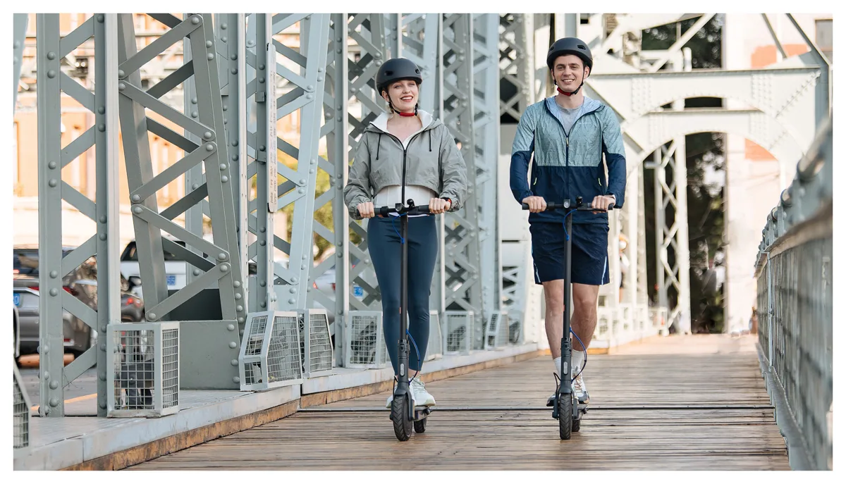 Deux personnes casquées roulant sur des Mi Electric Scooter 3 sur une passerelle