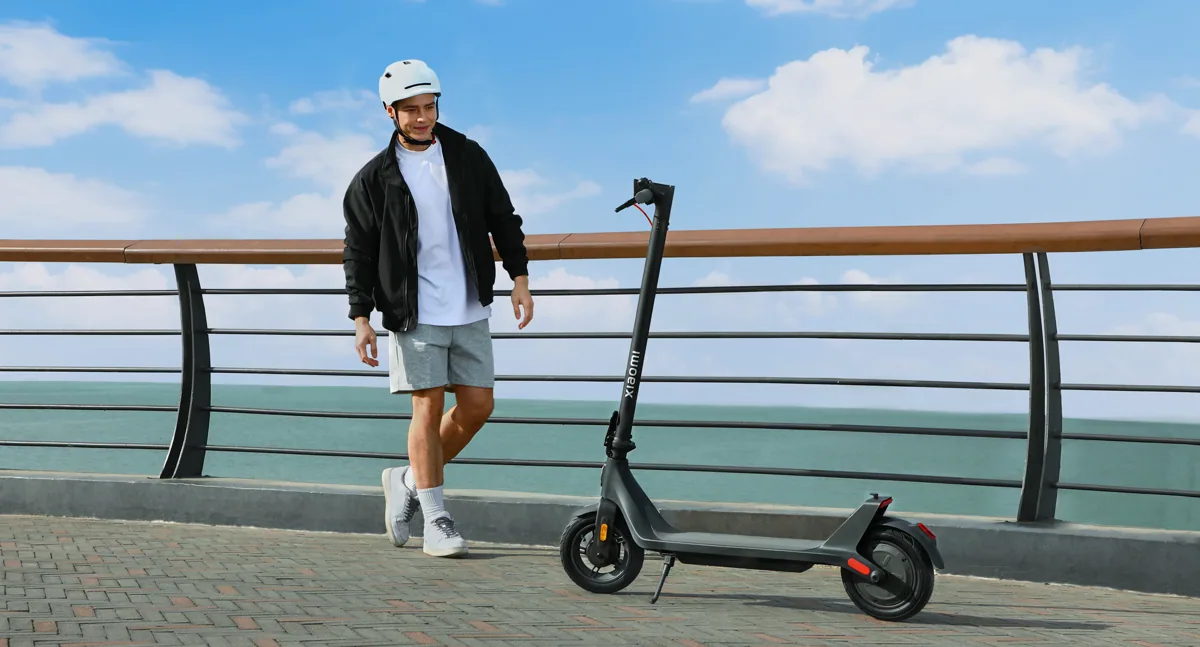 Personne qui marche à côté de la Xiaomi Electric Scooter 4 Lite (2e génération) au bord de l'eau