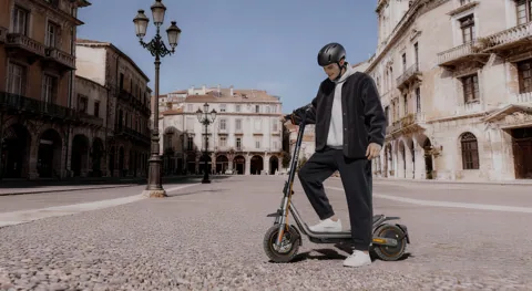 Personne debout à côté de la Xiaomi Electric Scooter 6 Pro sur une place pavée