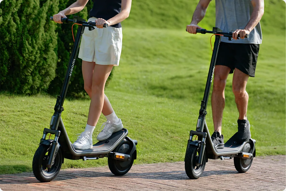 Deux personnes debout sur des Xiaomi Electric Scooter 6 sur une allée pavée