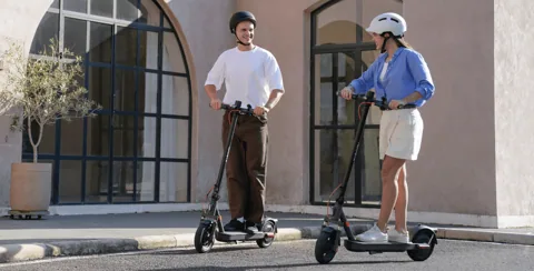 Deux personnes casquées sur des Xiaomi Electric Scooter Elite devant une maison