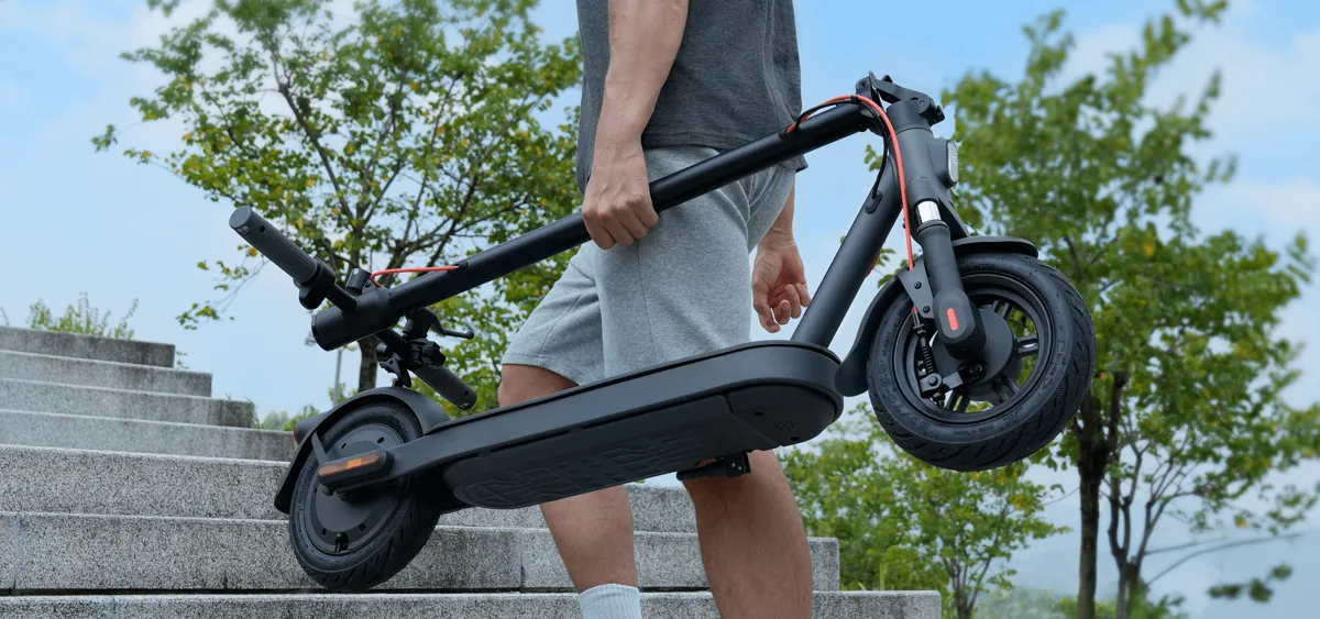 Personne qui porte la Xiaomi Electric Scooter Elite pliée dans un escalier